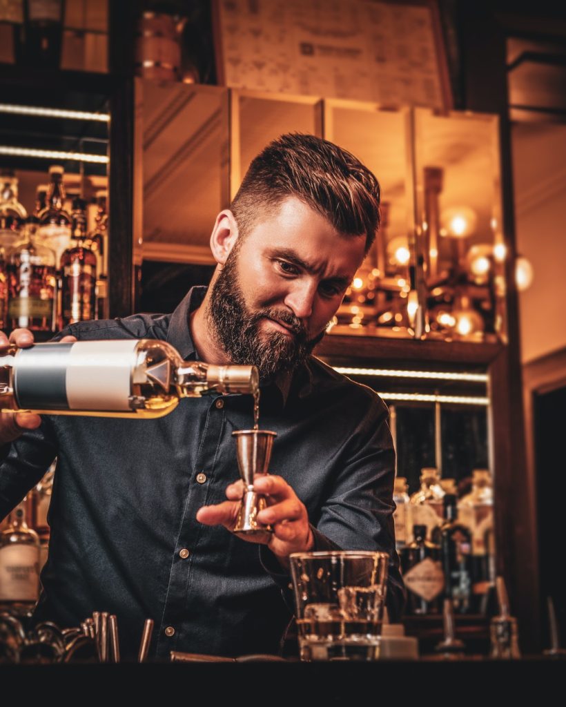 Bar tender preparando bebidas en la barra, mostrando su habilidad y profesionalismo en la creación de cócteles